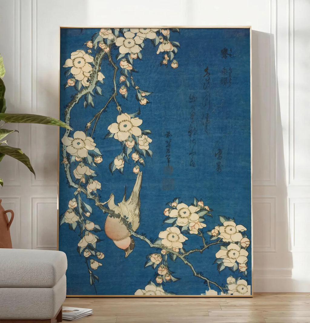 Reproduction affiche Hokusai bouvreuil sur cerisier pleureur en fleurs, posee au sol dans un salon minimaliste clair, a cote d'un canape beige et d'une plante verte, sur un parquet clair