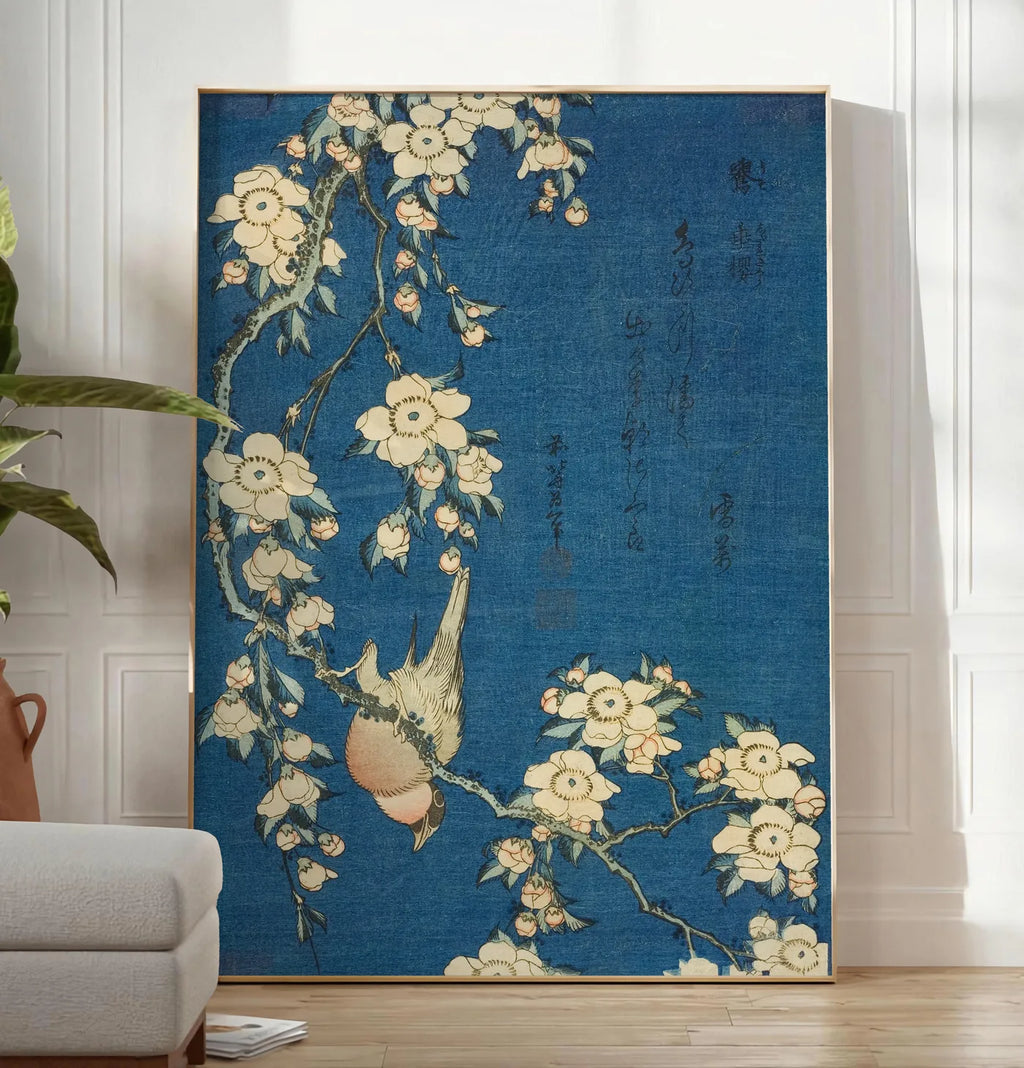 Reproduction affiche Hokusai cerisier en fleurs et bouvreuil, posee au sol dans un salon minimaliste clair, a cote d'un canape beige et d'une plante verte, sur un parquet clair