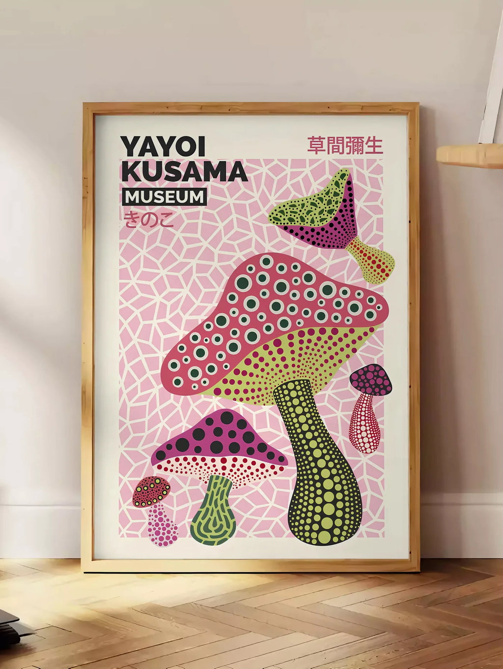 Estampe affiche champignons magenta de Kusama art japonais, posee au sol dans un coin salon, sur un parquet a chevrons, pres d'une table d'appoint en chene chargee de livres