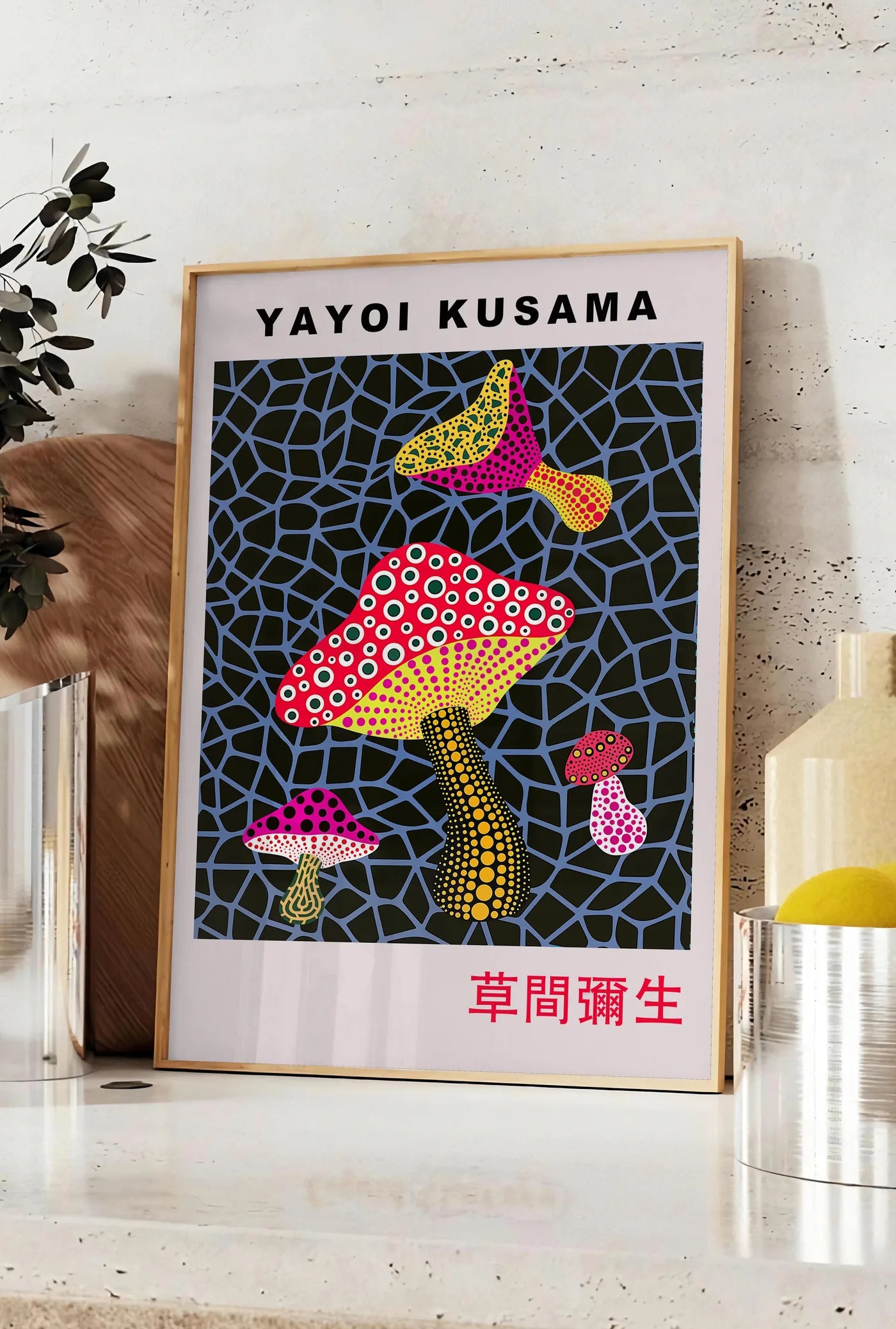 Affiche affiche champignons rouge de Kusama art japonais, posee sur un plan de travail de cuisine en pierre claire, entre une branche d'eucalyptus en vase et un bocal de citrons