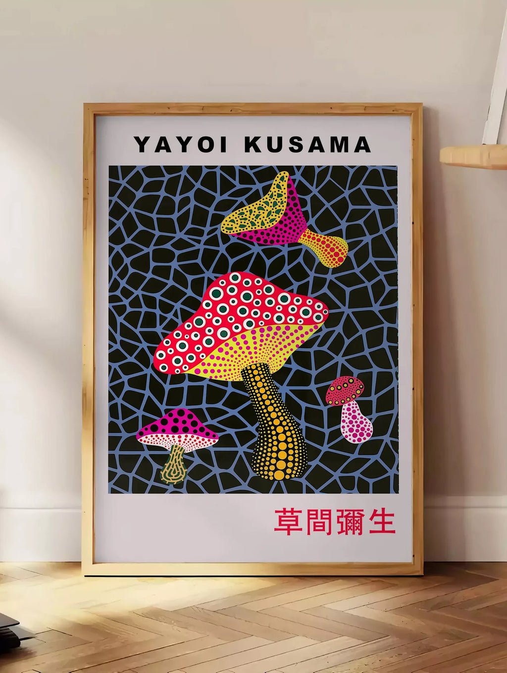 Estampe affiche champignons rouge de Kusama art japonais, posee au sol dans un coin salon, sur un parquet a chevrons, pres d'une table d'appoint en chene chargee de livres