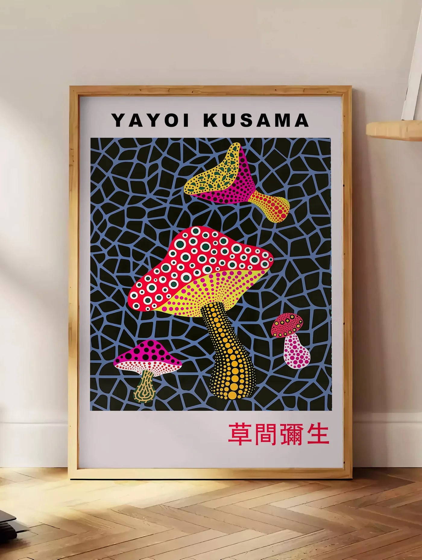 Estampe affiche champignons rouge de Kusama art japonais, posee au sol dans un coin salon, sur un parquet a chevrons, pres d'une table d'appoint en chene chargee de livres