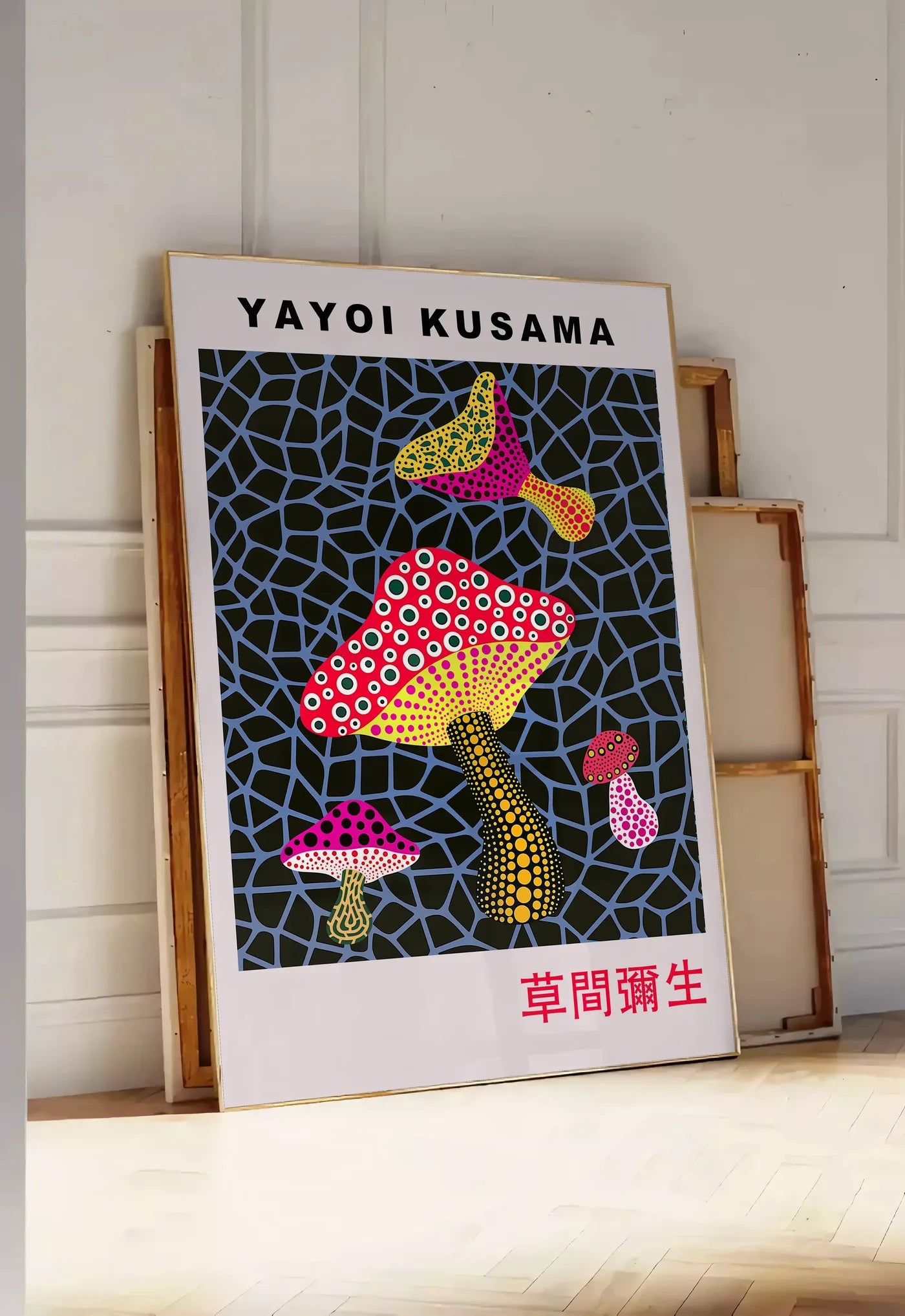 Tirage encadrable affiche champignons rouge de Kusama art japonais, posee au sol dans une entree lumineuse, contre un mur a panneaux blancs, a cote de chassis en bois empiles
