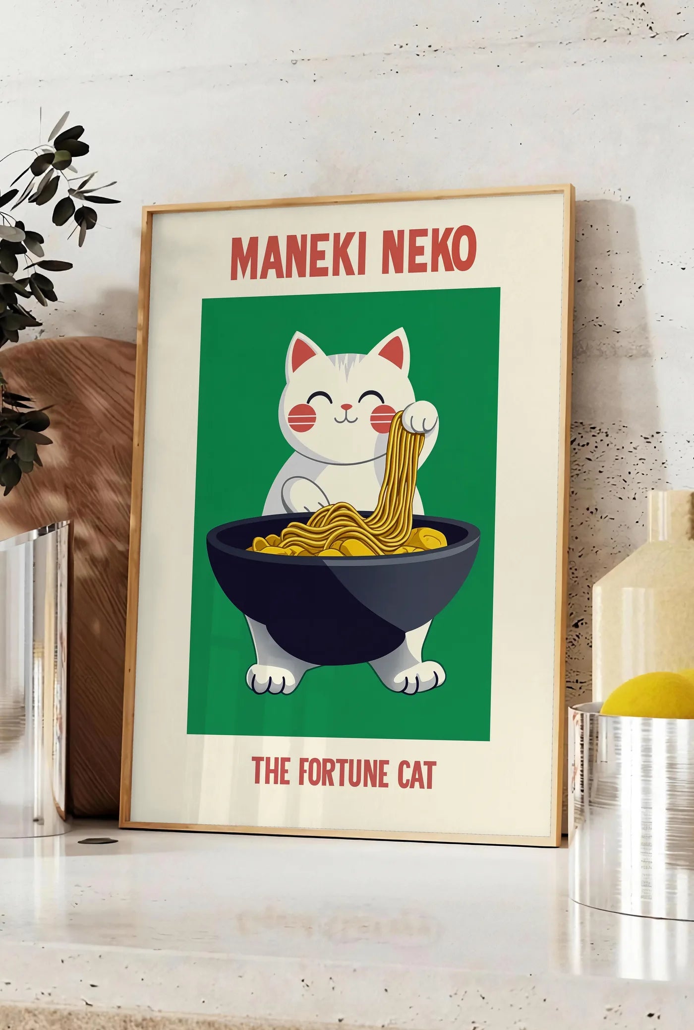 Affiche affiche Maneki Neko chat porte-bonheur tirant un fil de ramen d'un grand bol noir, posee sur un plan de travail de cuisine en pierre claire, entre une branche d'eucalyptus en vase et un bocal de citrons