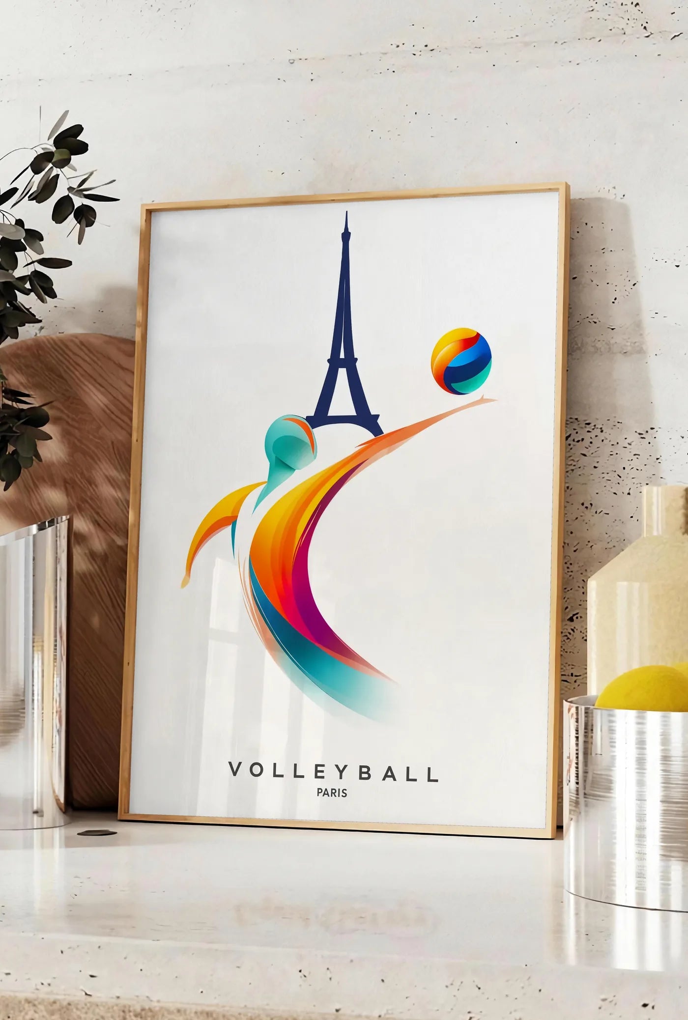 Affiche joueur de volley stylisé devant la silhouette de la Tour Eiffel, posee sur un plan de travail de cuisine en pierre claire, entre une branche d'eucalyptus en vase et un bocal de citrons